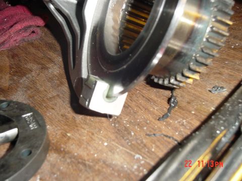1987 Ford Bronco - A close-up view of a damaged transmission gear and part of its housing, resting on a wooden surface.