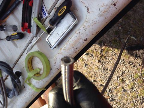 1979 Ford Bronco - Tools are laid out on a white surface next to a hose being held by a gloved hand.