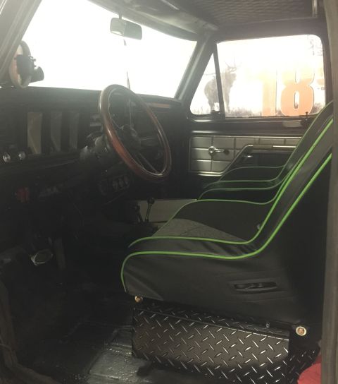 1979 Ford Bronco - The interior of a 1979 Ford Bronco features custom racing seats with green trim and a wooden steering wheel.