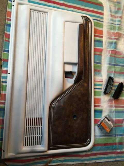1978 Ford Bronco - A disassembled car door panel with wood grain trim and speaker grille is laid out on a striped cloth.