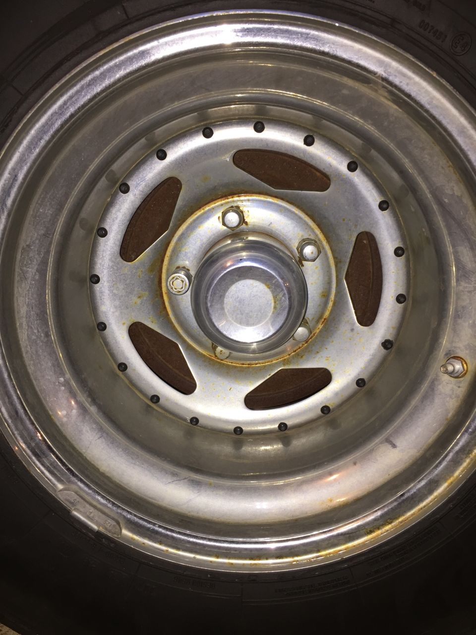 Chrome wheel with lug nuts and tire, close-up