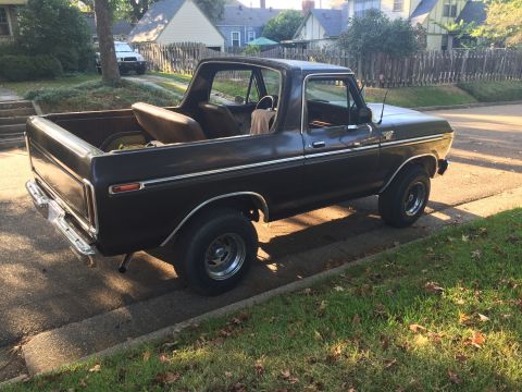 1978 Ford Bronco - dark brown vintage pickup truck with an open bed sits on a driveway in a suburban neighborhood, rear doors removed.