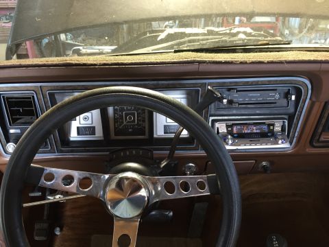 1978 Ford Bronco - The interior of a 1978 Ford Bronco shows a brown dashboard with an aftermarket stereo and a custom steering wheel.