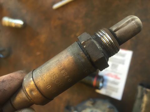 1995 Ford Bronco - A close-up shot of a used Bosch oxygen sensor with visible markings. The sensor has a threaded section and a ceramic tip, and appears to be…