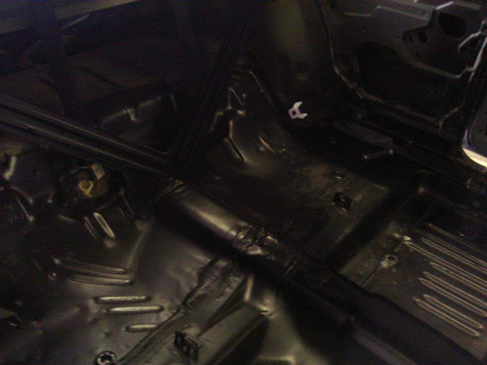 Interior of a classic car with black floor pan and exhaust tunnel.