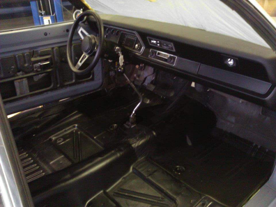 Interior view of a classic Dodge Dart during restoration, showing dashboard, steering wheel, and floor pans.