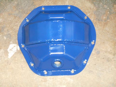 1972 Ford Bronco - A bright blue, aftermarket differential cover is shown from a top-down perspective, mounted on a concrete surface. The cover features a rei…