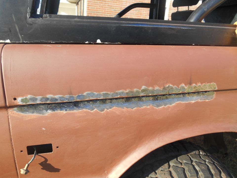 Close-up of a rusted and repaired fender on a classic Ford Bronco.