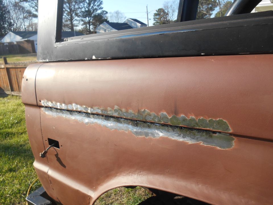 Close-up of rusted and welded seam on a brown 1972 Ford Bronco quarter panel.