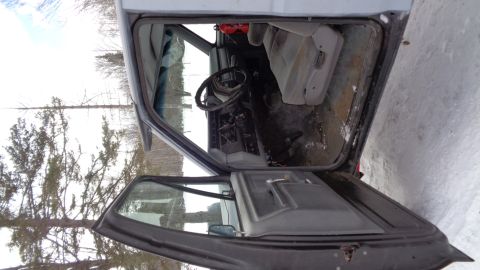 1985 Ford Bronco - The interior of a dark-colored vehicle, likely a truck or SUV, is visible with the driver's side door open. The dashboard, steering wheel,…