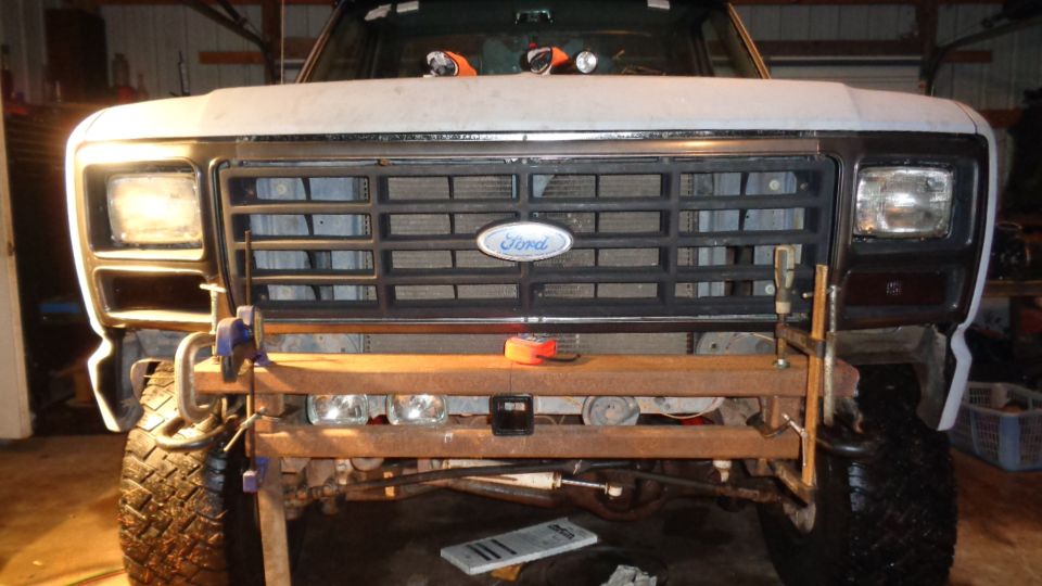 Front view of a Ford Bronco with a wooden bumper and clamps attached.