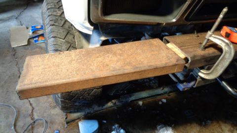 1985 Ford Bronco - A close-up view shows a rusty metal rectangular tube clamped to the frame of a vehicle, possibly for a modification. The tire and part of t…
