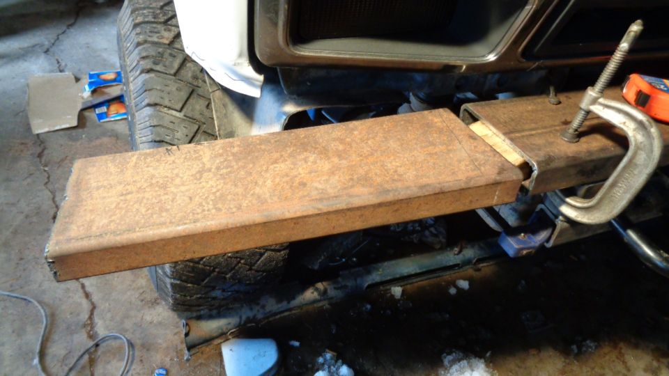 Rusty metal tube clamped to vehicle frame near tire