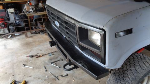 1985 Ford Bronco - The front of a light-colored vehicle, possibly a Ford Bronco, is shown with a black aftermarket bumper installed. Tools are scattered on th…