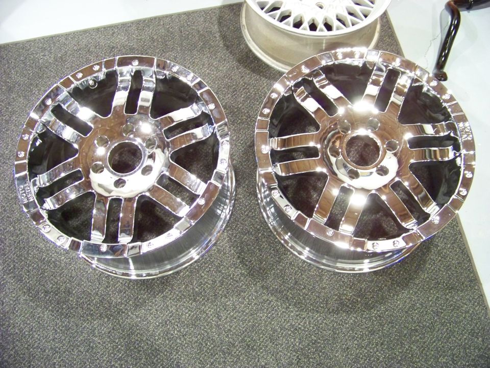 Two shiny chrome aftermarket truck wheels with a multi-spoke design.
