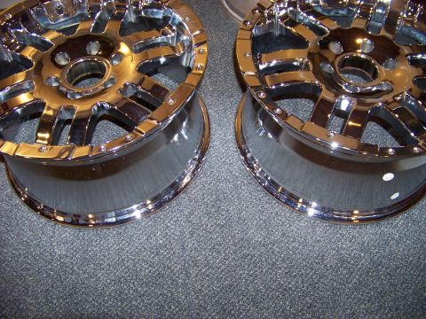 2005 Ford F-150 - Two shiny chrome aftermarket wheels are shown sitting on a gray carpeted surface. The wheels have a multi-spoke design with visible lug nut…