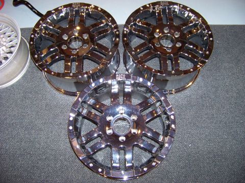 2005 Ford F-150 - Three chrome Moto Metal wheels are displayed on a dark grey carpeted surface. One wheel is partially visible on the left, and two are stack…