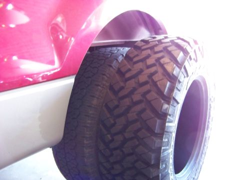 2005 Ford F-150 - A close-up side view shows a large, aggressive tread off-road tire mounted on a vehicle with a bright pink fender and a white lower body pa…