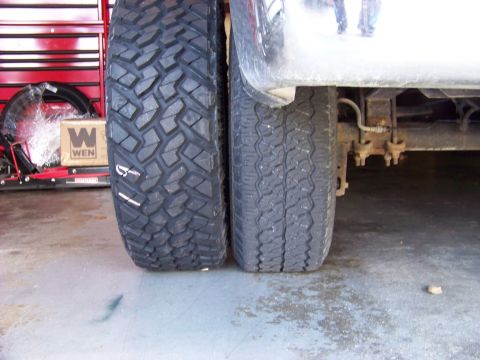 2005 Ford F-150 - A close-up view of the rear tires of a pickup truck, showing a larger off-road tire next to a standard tire. A red tool chest and a WEN box…