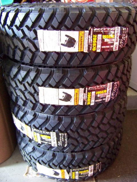 2005 Ford F-150 - A stack of four new LT275/70R18 125Q tires with "Trail Grappler" branding are shown, each with a warning label attached.