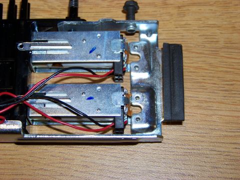 1999 Mercury Grand Marquis - A close-up view of two small electric motors with red and black wires attached, mounted on a metal bracket. A black rubber bumper is visibl…