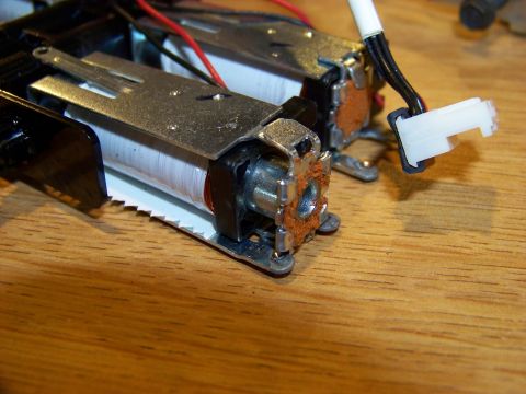 1999 Mercury Grand Marquis - Close-up view of two electromagnetic coils with copper windings, mounted on a wooden surface. A white electrical connector with black and r…