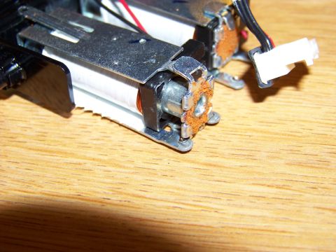 1999 Mercury Grand Marquis - Close-up view of two small electric motors with copper wire windings, mounted on a wooden surface. One motor has a white electrical connect…
