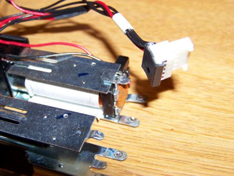 1999 Mercury Grand Marquis - A close-up view of a solenoid coil with a white connector and black and red wires attached, resting on a wooden surface.