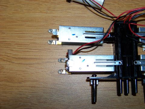 1999 Mercury Grand Marquis - Close-up view of two silver metal components with red and black wires attached, mounted on a black plastic base. The components are positio…