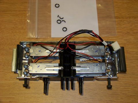 1999 Mercury Grand Marquis - A close-up view of a mechanical assembly with multiple small motors, wiring, and screws, mounted on a wooden surface. A clear plastic bag w…