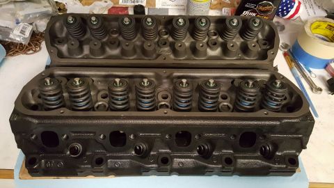 1996 Ford Bronco - A matched pair of rebuilt cast-iron V8 cylinder heads sitting on a workbench, freshly painted dark gray with new valve springs, retainers a…