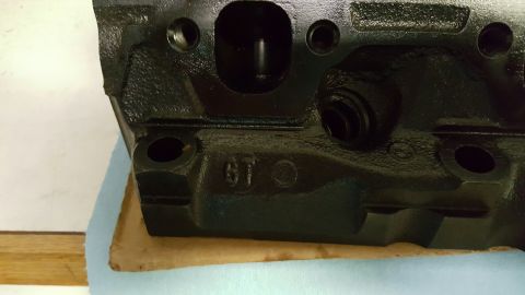 1996 Ford Bronco - A close-up, low-angle shot shows the black cast iron engine block of a 1996 Ford Bronco. The block has visible casting marks, including "6T…