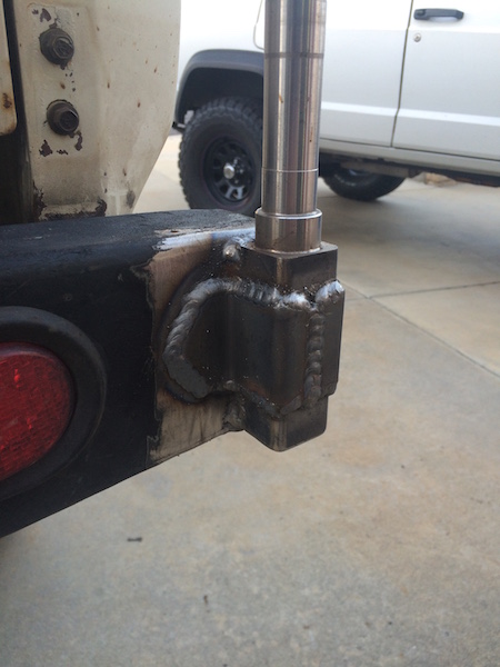 1981 Ford Bronco - A close-up view of a custom-welded metal bracket attached to the rear bumper of a vehicle. A silver metal pole extends vertically from the…