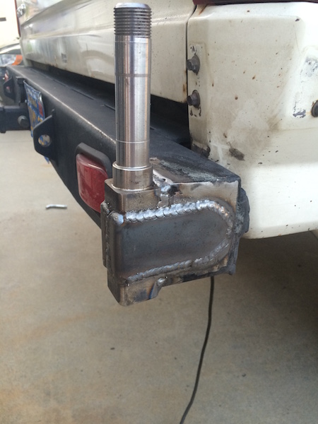 1981 Ford Bronco - A close-up view of a custom-fabricated steel bracket welded to the rear bumper of a vehicle. A metal spindle protrudes vertically from the…