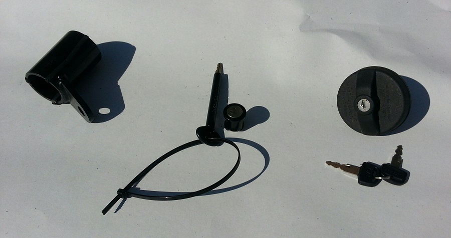 Black fuel cap, two keys, mounting bracket, and cable tie on white surface.