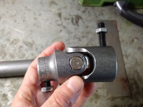 1992 Ford Bronco - A close-up of a steering shaft universal joint, held in a hand, with visible text and hardware.