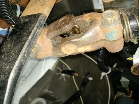 1992 Ford Bronco - Close-up of a rusty steering shaft universal joint assembly with surrounding wiring and conduit.