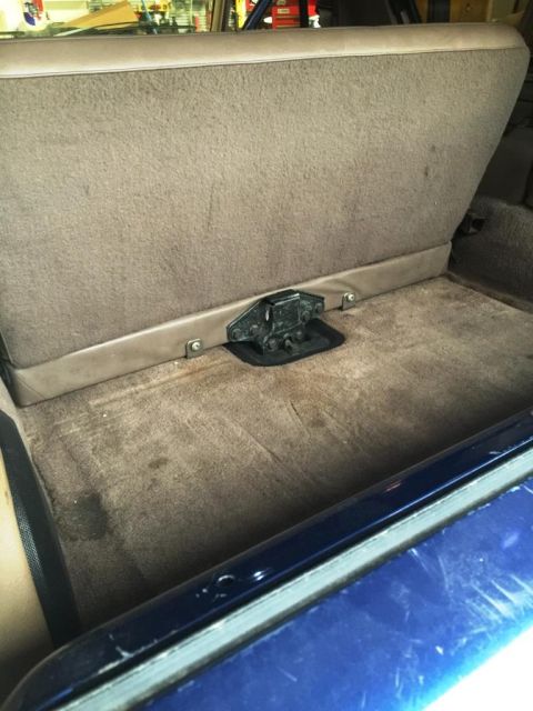 1996 Ford Bronco - The interior of a vehicle shows the rear seat and carpeted floor with a visible latch mechanism.