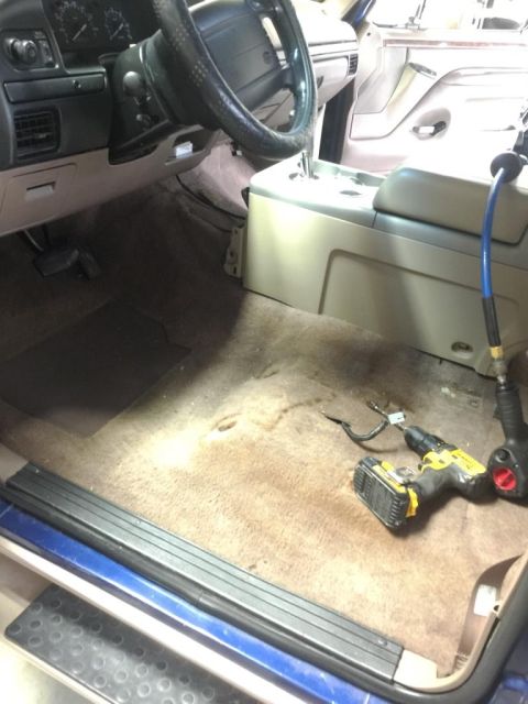 1996 Ford Bronco - The interior of a 1996 Ford Bronco is visible, with tools laid out on the carpeted floor.