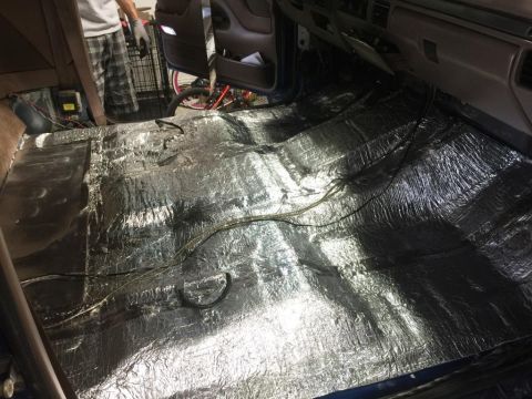 1996 Ford Bronco - The interior floor of a vehicle is covered with sound deadening material and wiring during a repair or modification.