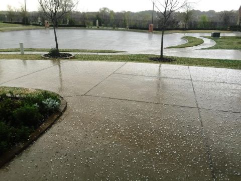 1996 Ford Bronco - A residential driveway is covered in small hailstones following a storm, with a pond and trees in the background.