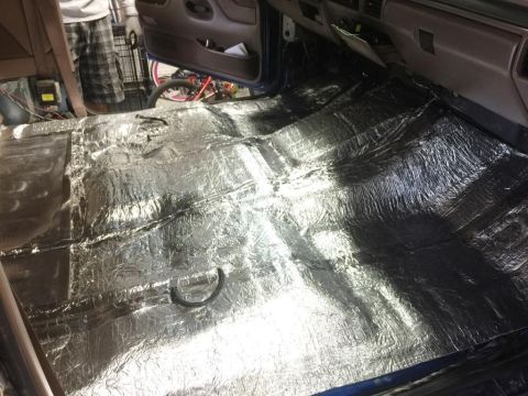 1996 Ford Bronco - Sound deadening material being installed on the floor of a vehicle's interior.