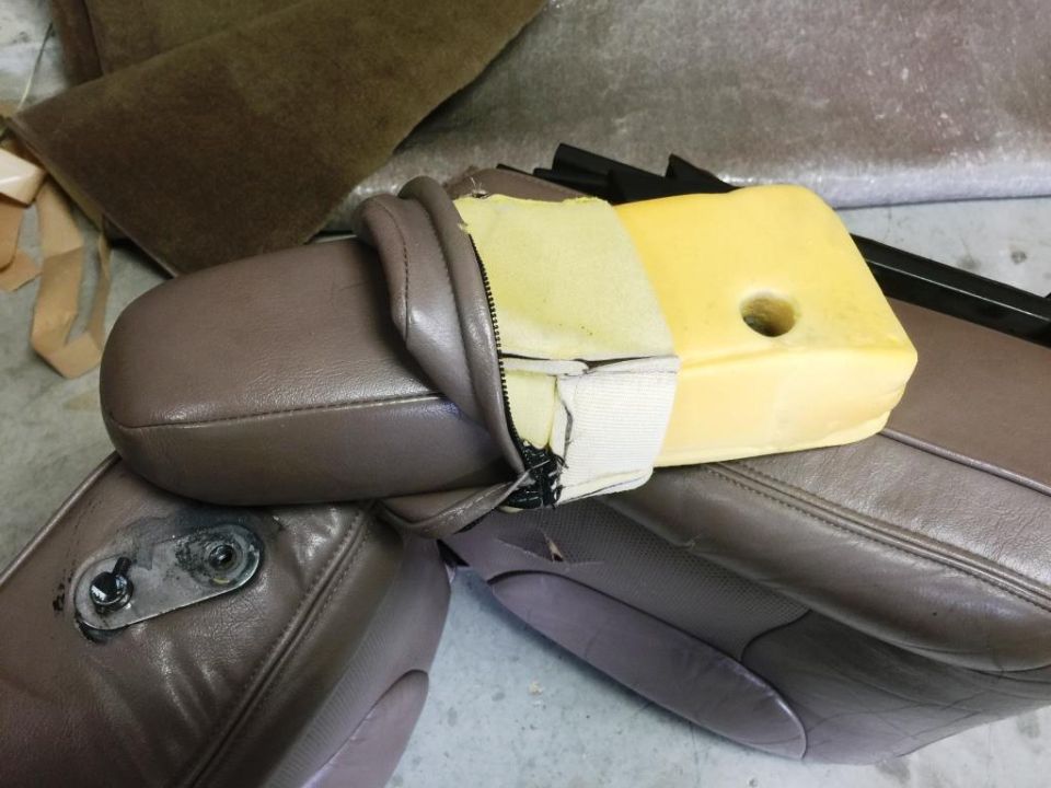 close-up of car seat cushion with exposed foam and torn upholstery