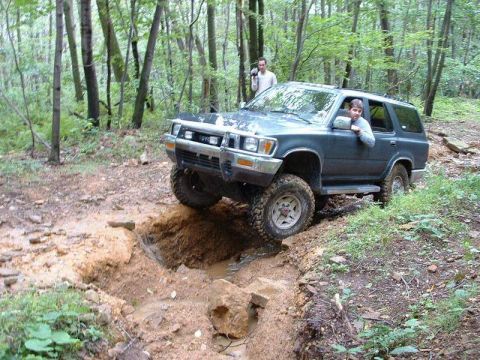 1978 Ford Bronco - A Toyota 4Runner navigates a challenging muddy trail in a forest setting.
