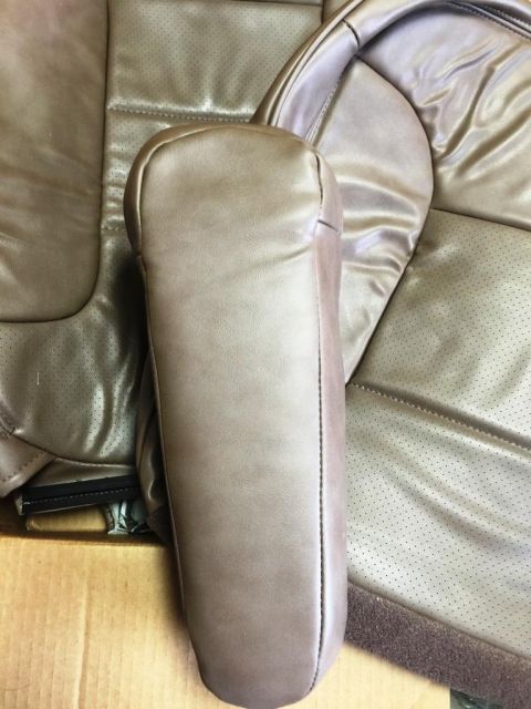 1996 Ford Bronco - Close-up of a car's interior, showing a tan leather armrest and perforated seat material.
