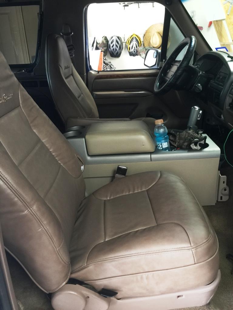 Tan leather seats and center console of a 1996 Ford Bronco, with a water bottle and other items on the console