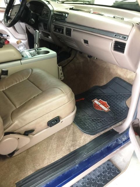 1996 Ford Bronco - The interior of a truck is shown, a tan leather seat and a Harley-Davidson branded floor mat on the passenger side.