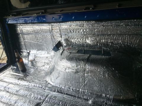 1996 Ford Bronco - Soundproofing is being installed in the interior of a vehicle, with a bottle of beer resting on the floor.