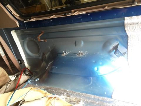 1996 Ford Bronco - The rear interior of a vehicle shows exposed metal and mounting hardware, with a speaker cutout visible.