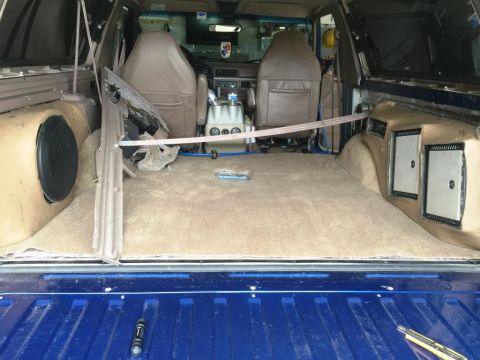 1996 Ford Bronco - The rear interior of an SUV is carpeted and features custom speaker enclosures on both sides.